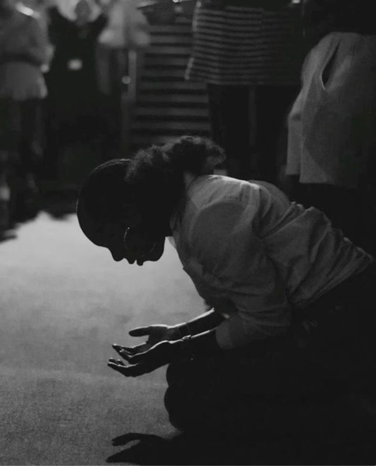 Black-and-white photograph of a woman kneeling in prayer with open hands